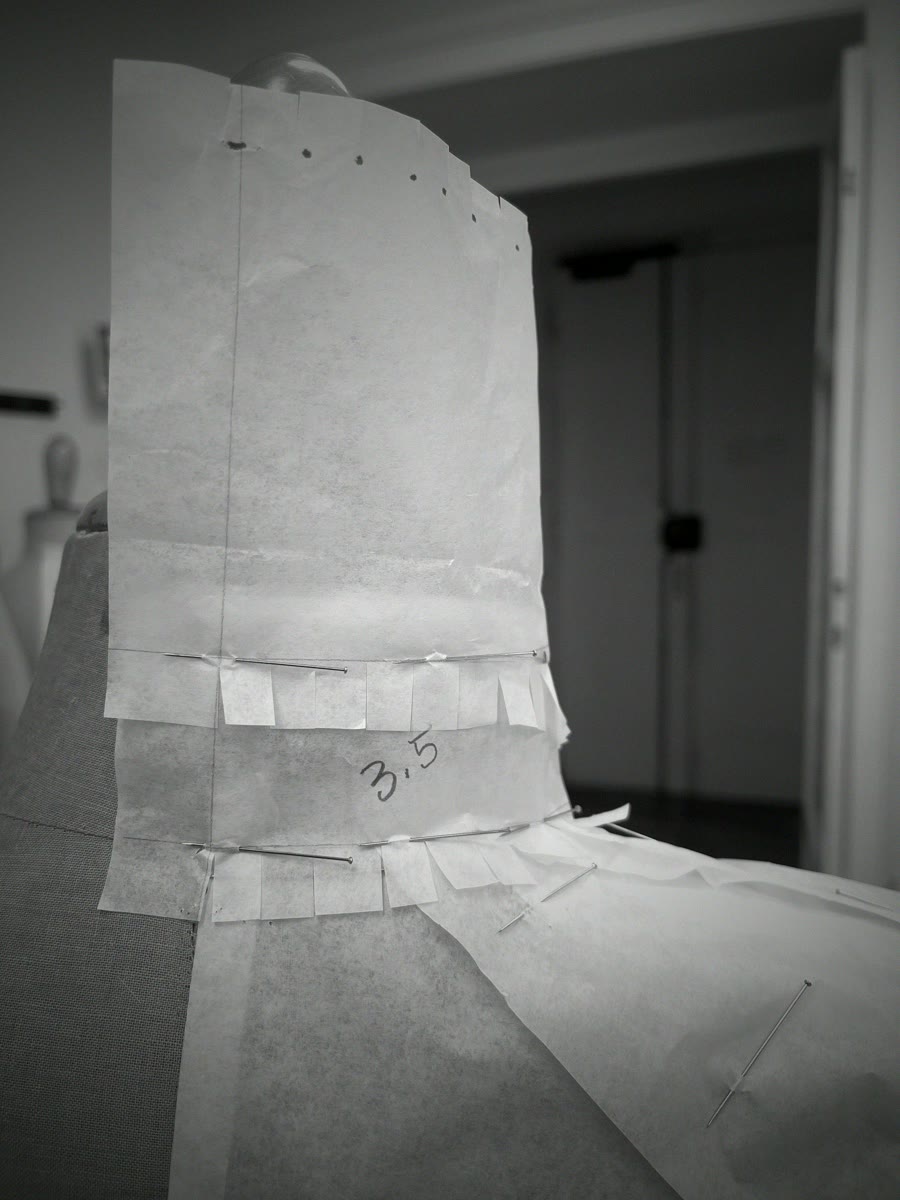 A collar draped and pinned in pattern paper on the mannequin, our moulage method