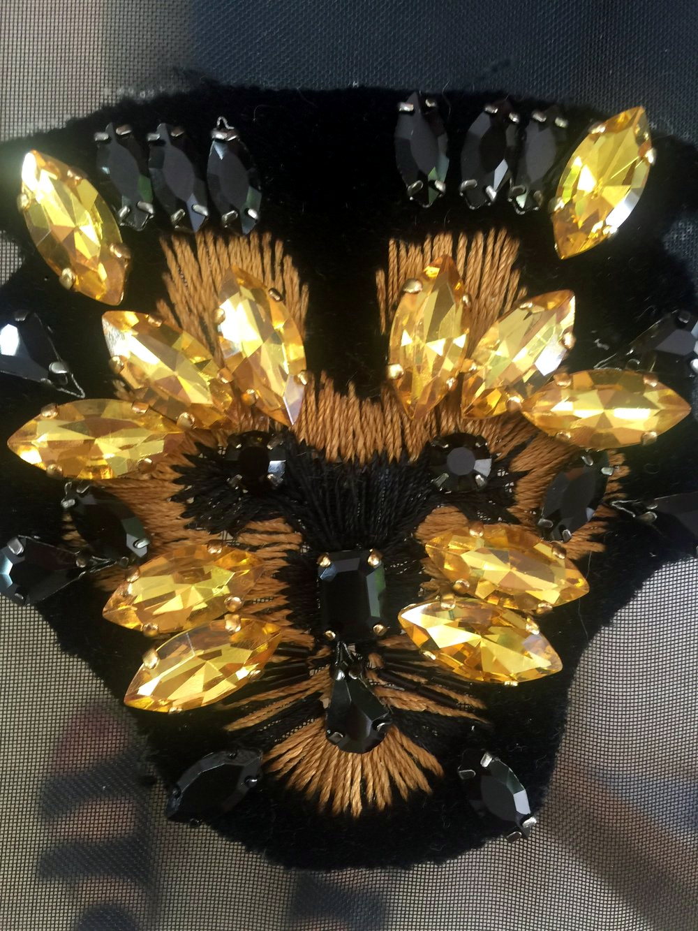 A gold marquise-crystal and bead sunburst motif on black