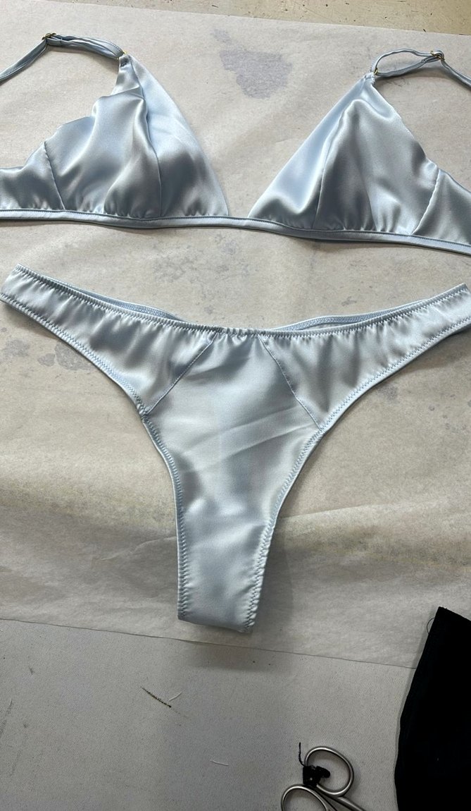 A pale-blue silk charmeuse bralette and thong set, laid flat