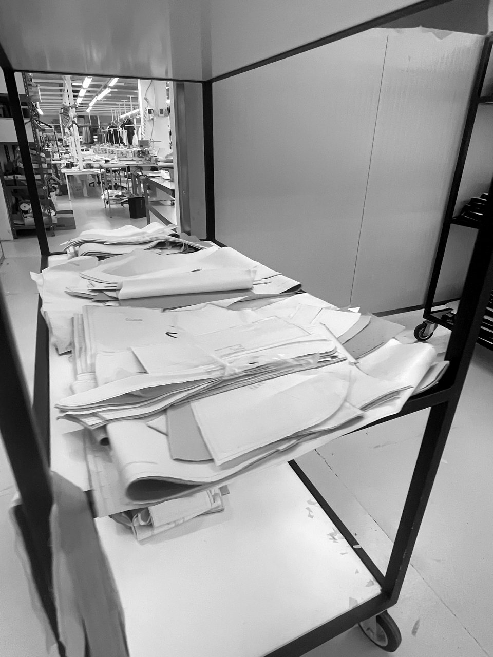 A rolling cart stacked with folded paper patterns and toiles in the atelier