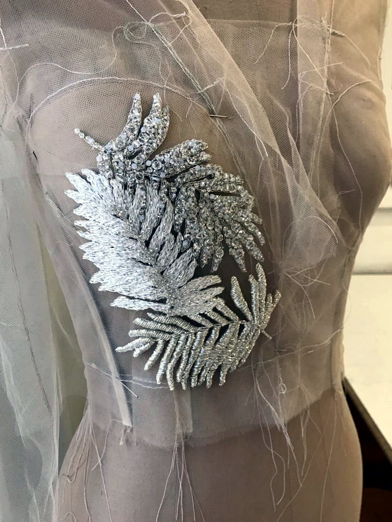 A silver fern beaded appliqu&eacute; held against sheer tulle