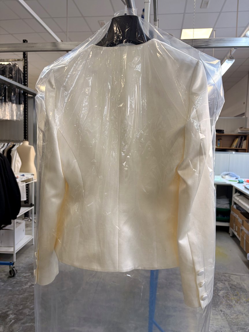 A tailored silk-satin womenswear jacket with self-covered buttons, on the form
