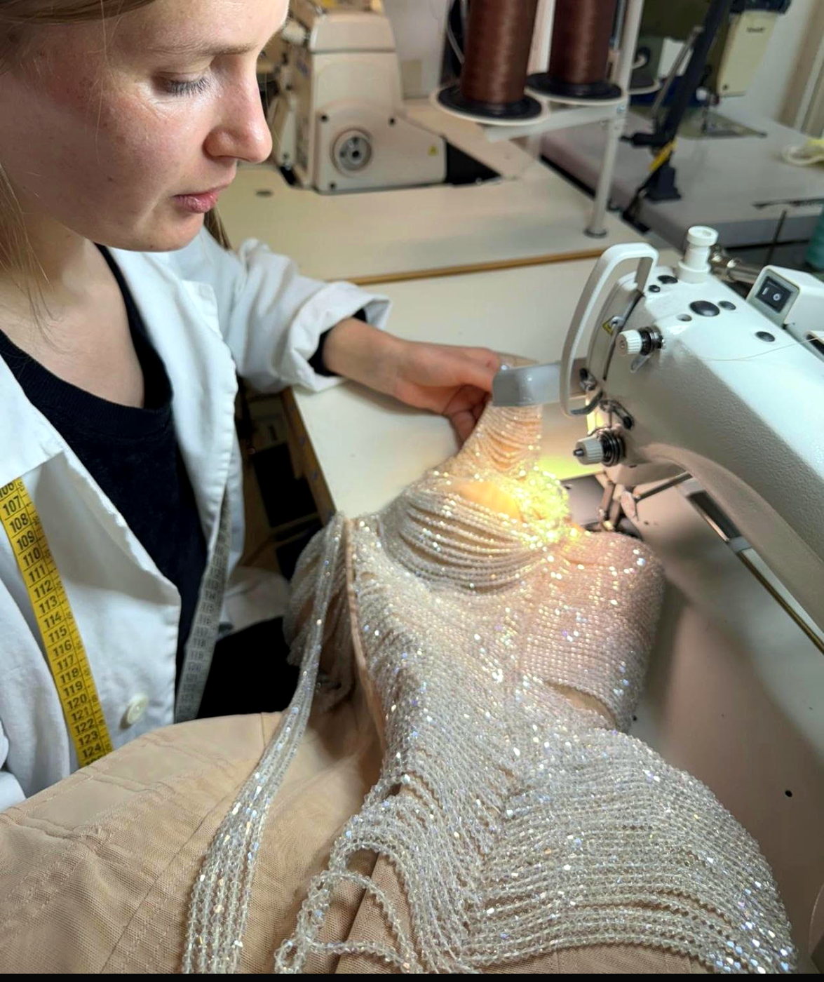 An embroiderer working the beaded gown at the machine