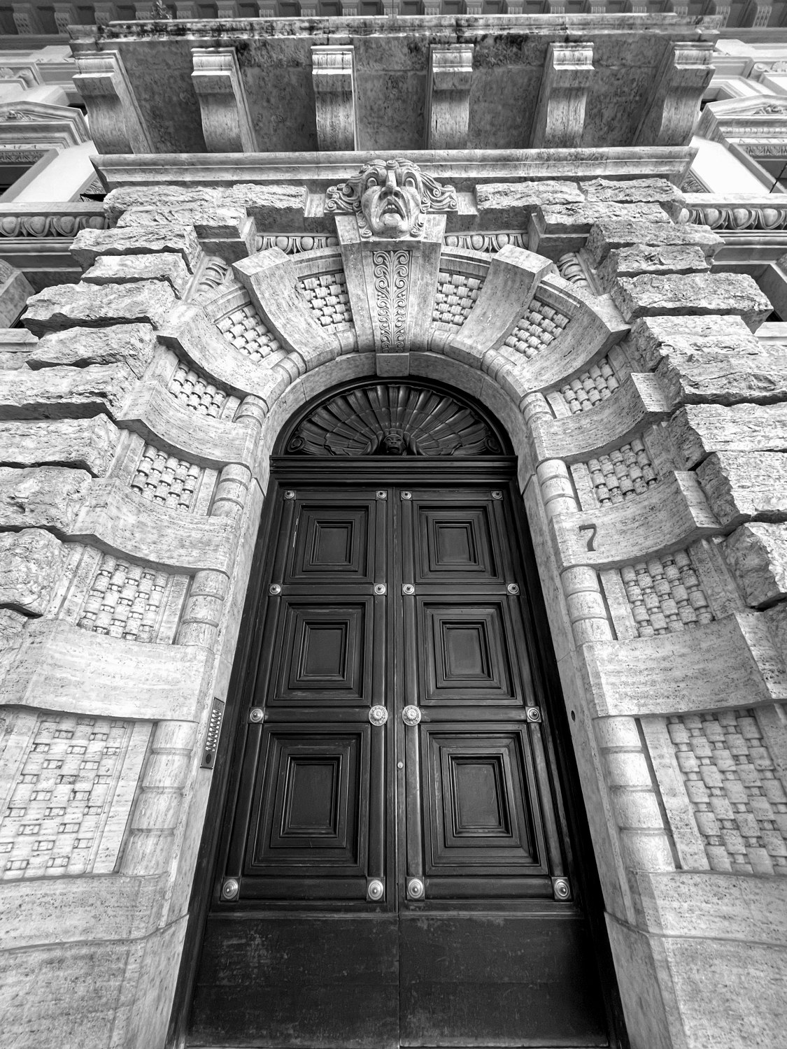 An ornate stone doorway with grand dark wooden doors
