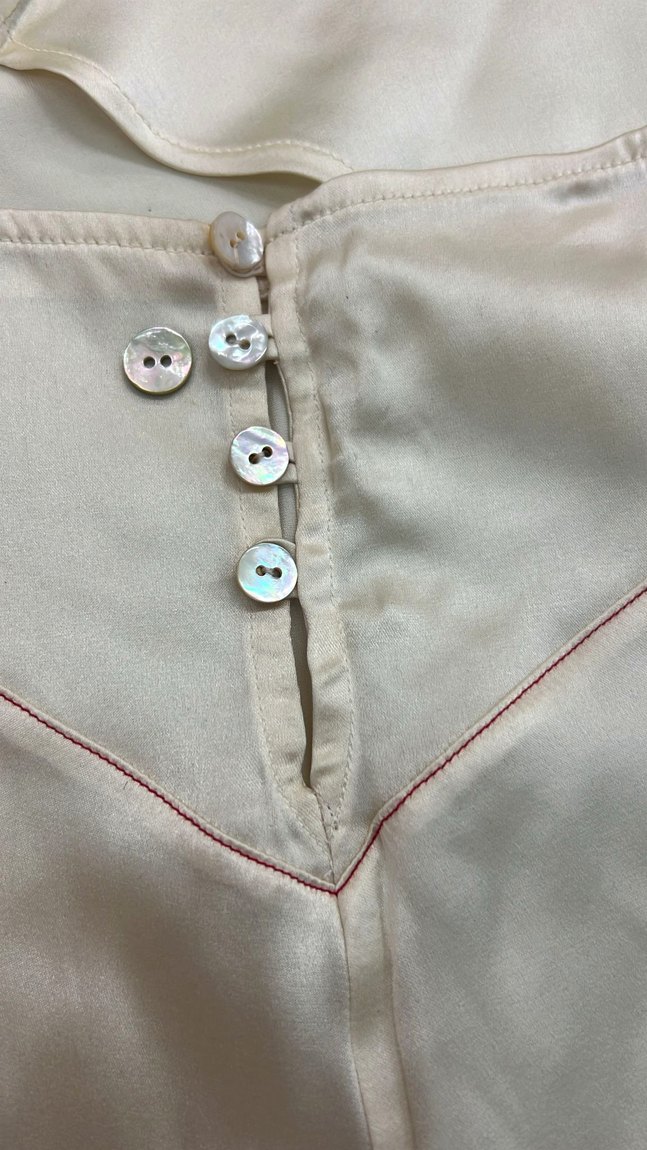 The back of a silk short with mother-of-pearl button closures and contrast topstitch