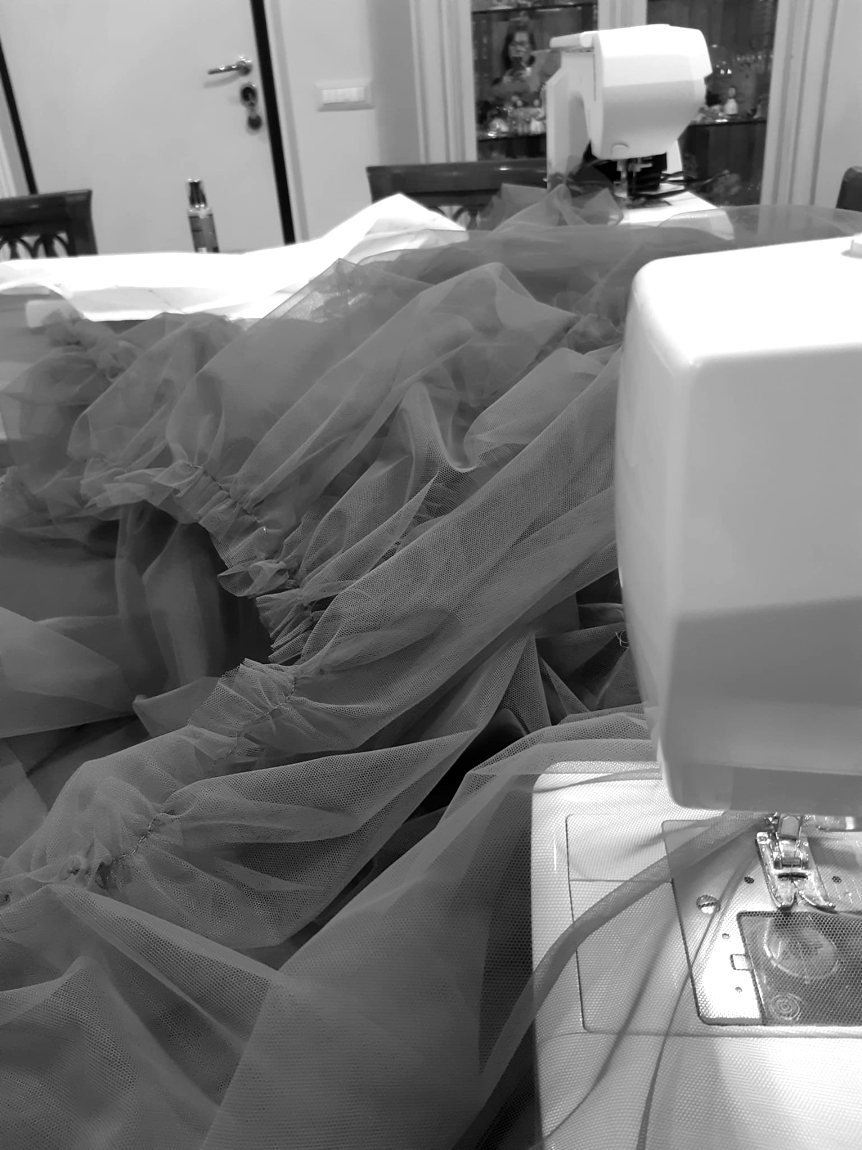 The tulle skirt of a dress being gathered and sewn at the machine